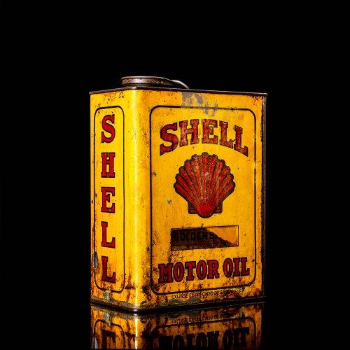 Vintage Shell oil cans with red and yellow branding from the 1900-1920 old logo Vintage Shell oil cans from 1900-19255, featuring the old logo. The photo showcases an antique tin red with yellow accents, displaying the historic Shell emblem. Shot in a studio against a solid black background