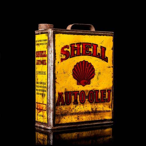 Vintage Shell oil cans with red and yellow branding from the 1900-1920 old logo Vintage Shell oil cans from 1900-19255, featuring the old logo. The photo showcases an antique tin red with yellow accents, displaying the historic Shell emblem. Shot in a studio against a solid black background