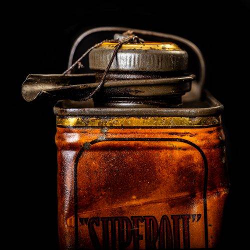 Vintage Shell oil cans with red and yellow branding from the 1900-1920 old logo Vintage Shell oil cans from 1900-19255, featuring the old logo. The photo showcases an antique tin red with yellow accents, displaying the historic Shell emblem. Shot in a studio against a solid black background