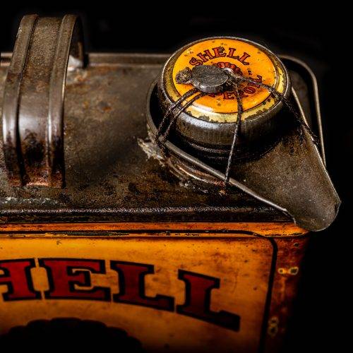 Vintage Shell oil cans with red and yellow branding from the 1900-1920 old logo Vintage Shell oil cans from 1900-19255, featuring the old logo. The photo showcases an antique tin red with yellow accents, displaying the historic Shell emblem. Shot in a studio against a solid black background