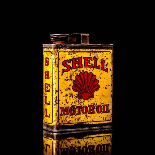 Vintage Shell oil cans with red and yellow branding from the 1900-1920 old logo Vintage Shell oil cans from 1900-19255, featuring the old logo. The photo showcases an antique tin red with yellow accents, displaying the historic Shell emblem. Shot in a studio against a solid black background