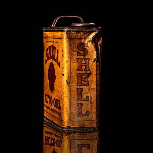 Vintage Shell oil cans with red and yellow branding from the 1900-1920 old logo Vintage Shell oil cans from 1900-19255, featuring the old logo. The photo showcases an antique tin red with yellow accents, displaying the historic Shell emblem. Shot in a studio against a solid black background