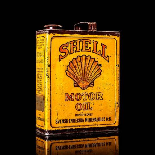 Vintage Shell oil cans with red and yellow branding from the 1900-1920 old logo Vintage Shell oil cans from 1900-19255, featuring the old logo. The photo showcases an antique tin red with yellow accents, displaying the historic Shell emblem. Shot in a studio against a solid black background