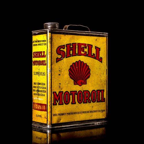 Vintage Shell oil cans with red and yellow branding from the 1900-1920 old logo Vintage Shell oil cans from 1900-19255, featuring the old logo. The photo showcases an antique tin red with yellow accents, displaying the historic Shell emblem. Shot in a studio against a solid black background
