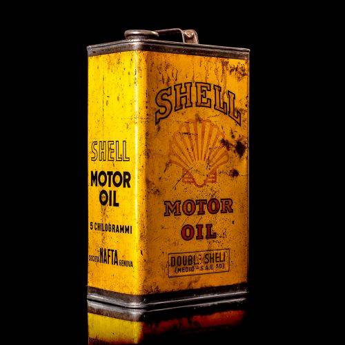Vintage Shell oil cans with red and yellow branding from the 1900-1920 old logo Vintage Shell oil cans from 1900-19255, featuring the old logo. The photo showcases an antique tin red with yellow accents, displaying the historic Shell emblem. Shot in a studio against a solid black background