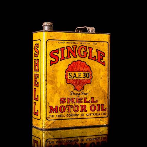 Vintage Shell oil cans with red and yellow branding from the 1900-1920 old logo Vintage Shell oil cans from 1900-19255, featuring the old logo. The photo showcases an antique tin red with yellow accents, displaying the historic Shell emblem. Shot in a studio against a solid black background