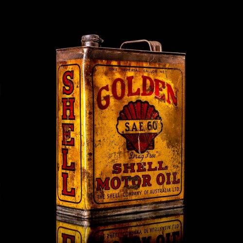 Vintage Shell oil cans with red and yellow branding from the 1900-1920 old logo Vintage Shell oil cans from 1900-19255, featuring the old logo. The photo showcases an antique tin red with yellow accents, displaying the historic Shell emblem. Shot in a studio against a solid black background