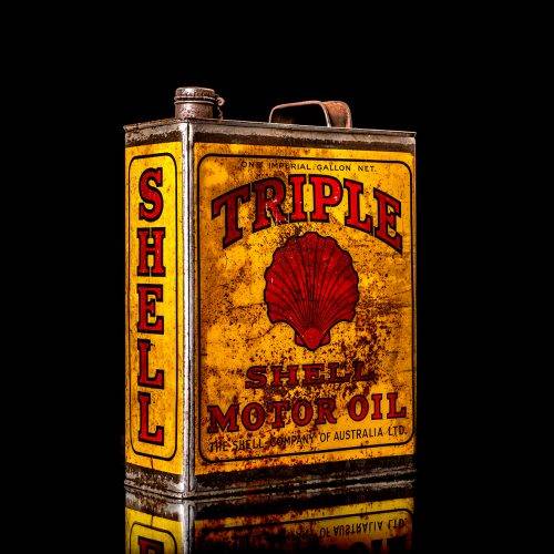 Vintage Shell oil cans with red and yellow branding from the 1900-1920 old logo Vintage Shell oil cans from 1900-19255, featuring the old logo. The photo showcases an antique tin red with yellow accents, displaying the historic Shell emblem. Shot in a studio against a solid black background