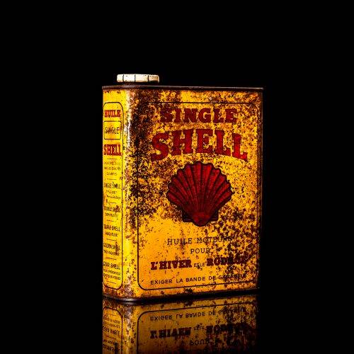 Vintage Shell oil cans with red and yellow branding from the 1900-1920 old logo Vintage Shell oil cans from 1900-19255, featuring the old logo. The photo showcases an antique tin red with yellow accents, displaying the historic Shell emblem. Shot in a studio against a solid black background