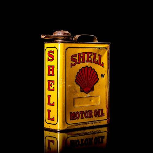 Vintage Shell oil cans with red and yellow branding from the 1900-1920 old logo Vintage Shell oil cans from 1900-19255, featuring the old logo. The photo showcases an antique tin red with yellow accents, displaying the historic Shell emblem. Shot in a studio against a solid black background