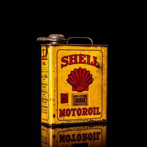 Vintage Shell oil cans with red and yellow branding from the 1900-1920 old logo Vintage Shell oil cans from 1900-19255, featuring the old logo. The photo showcases an antique tin red with yellow accents, displaying the historic Shell emblem. Shot in a studio against a solid black background