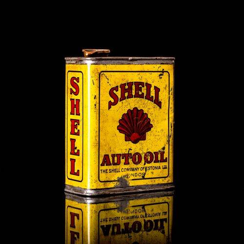 Vintage Shell oil cans with red and yellow branding from the 1900-1920 old logo Vintage Shell oil cans from 1900-19255, featuring the old logo. The photo showcases an antique tin red with yellow accents, displaying the historic Shell emblem. Shot in a studio against a solid black background