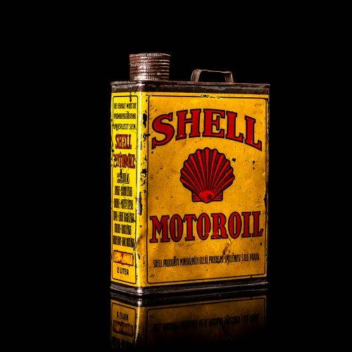 Vintage Shell oil cans with red and yellow branding from the 1900-1920 old logo Vintage Shell oil cans from 1900-19255, featuring the old logo. The photo showcases an antique tin red with yellow accents, displaying the historic Shell emblem. Shot in a studio against a solid black background
