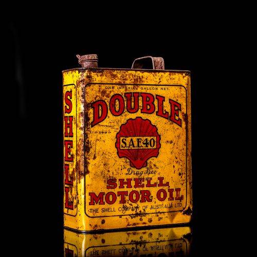 Vintage Shell oil cans with red and yellow branding from the 1900-1920 old logo Vintage Shell oil cans from 1900-19255, featuring the old logo. The photo showcases an antique tin red with yellow accents, displaying the historic Shell emblem. Shot in a studio against a solid black background