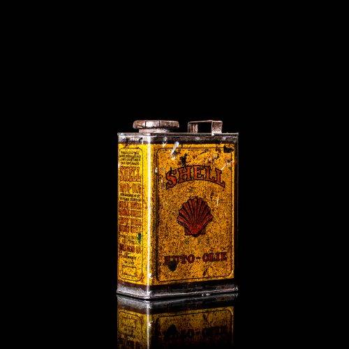 Vintage Shell oil cans with red and yellow branding from the 1900-1920 old logo Vintage Shell oil cans from 1900-19255, featuring the old logo. The photo showcases an antique tin red with yellow accents, displaying the historic Shell emblem. Shot in a studio against a solid black background
