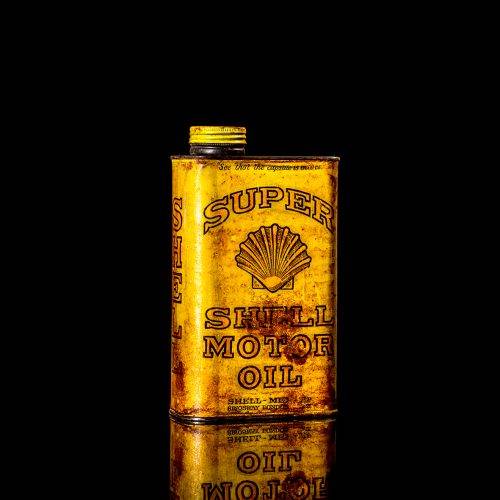 Vintage Shell oil cans with red and yellow branding from the 1900-1920 old logo Vintage Shell oil cans from 1900-19255, featuring the old logo. The photo showcases an antique tin red with yellow accents, displaying the historic Shell emblem. Shot in a studio against a solid black background