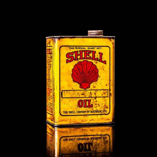 Vintage Shell oil cans with red and yellow branding from the 1900-1920 old logo Vintage Shell oil cans from 1900-19255, featuring the old logo. The photo showcases an antique tin red with yellow accents, displaying the historic Shell emblem. Shot in a studio against a solid black background
