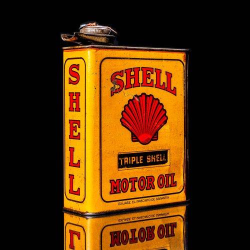Vintage Shell oil cans with red and yellow branding from the 1900-1920 old logo Vintage Shell oil cans from 1900-19255, featuring the old logo. The photo showcases an antique tin red with yellow accents, displaying the historic Shell emblem. Shot in a studio against a solid black background