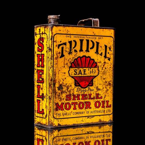 Vintage Shell oil cans with red and yellow branding from the 1900-1920 old logo Vintage Shell oil cans from 1900-19255, featuring the old logo. The photo showcases an antique tin red with yellow accents, displaying the historic Shell emblem. Shot in a studio against a solid black background