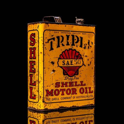 Vintage Shell oil cans with red and yellow branding from the 1900-1920 old logo Vintage Shell oil cans from 1900-19255, featuring the old logo. The photo showcases an antique tin red with yellow accents, displaying the historic Shell emblem. Shot in a studio against a solid black background