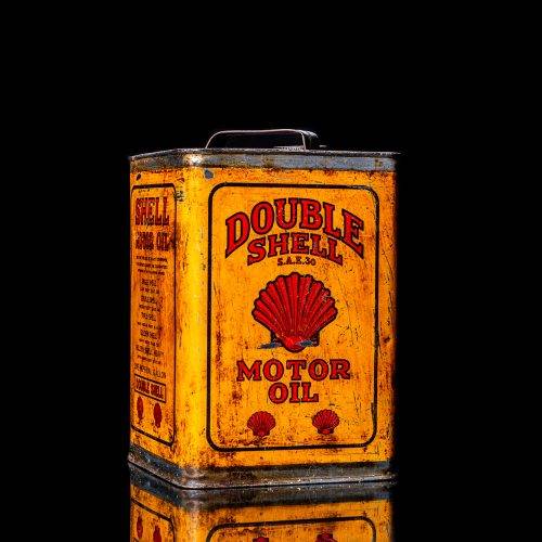 Vintage Shell oil cans with red and yellow branding from the 1900-1920 old logo Vintage Shell oil cans from 1900-19255, featuring the old logo. The photo showcases an antique tin red with yellow accents, displaying the historic Shell emblem. Shot in a studio against a solid black background