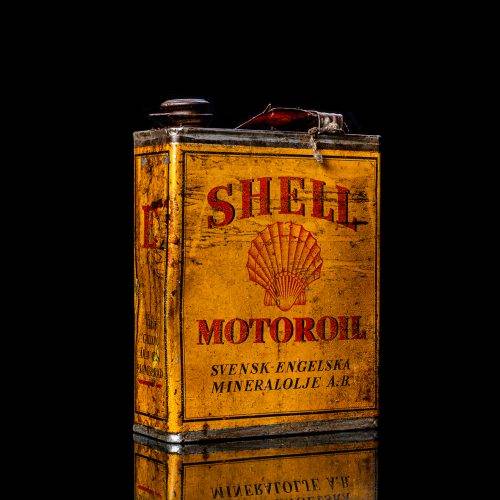 Vintage Shell oil cans with red and yellow branding from the 1900-1920 old logo Vintage Shell oil cans from 1900-19255, featuring the old logo. The photo showcases an antique tin red with yellow accents, displaying the historic Shell emblem. Shot in a studio against a solid black background