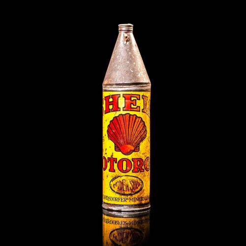 Vintage Shell oil cans with red and yellow branding from the 1900-1920 old logo Vintage Shell oil cans from 1900-19255, featuring the old logo. The photo showcases an antique tin red with yellow accents, displaying the historic Shell emblem. Shot in a studio against a solid black background