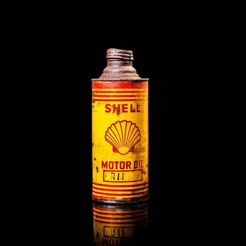Vintage Shell oil cans with red and yellow branding from the 1900-1920 old logo Vintage Shell oil cans from 1900-19255, featuring the old logo. The photo showcases an antique tin red with yellow accents, displaying the historic Shell emblem. Shot in a studio against a solid black background