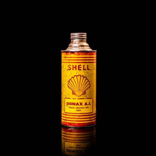 Vintage Shell oil cans with red and yellow branding from the 1900-1920 old logo Vintage Shell oil cans from 1900-19255, featuring the old logo. The photo showcases an antique tin red with yellow accents, displaying the historic Shell emblem. Shot in a studio against a solid black background