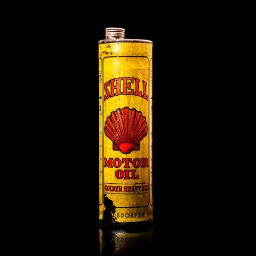 Vintage Shell oil cans with red and yellow branding from the 1900-1920 old logo Vintage Shell oil cans from 1900-19255, featuring the old logo. The photo showcases an antique tin red with yellow accents, displaying the historic Shell emblem. Shot in a studio against a solid black background