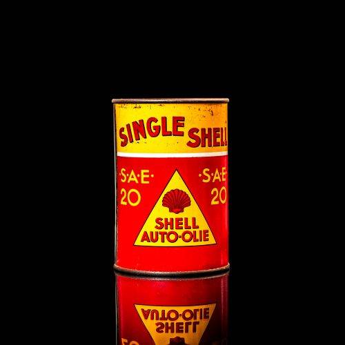 Vintage Shell oil cans with red and yellow branding from the 1900-1920 old logo Vintage Shell oil cans from 1900-19255, featuring the old logo. The photo showcases an antique tin red with yellow accents, displaying the historic Shell emblem. Shot in a studio against a solid black background