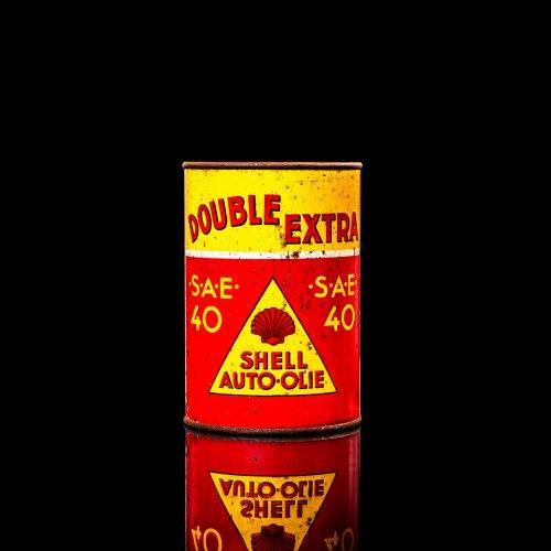 Vintage Shell oil cans with red and yellow branding from the 1900-1920 old logo Vintage Shell oil cans from 1900-19255, featuring the old logo. The photo showcases an antique tin red with yellow accents, displaying the historic Shell emblem. Shot in a studio against a solid black background