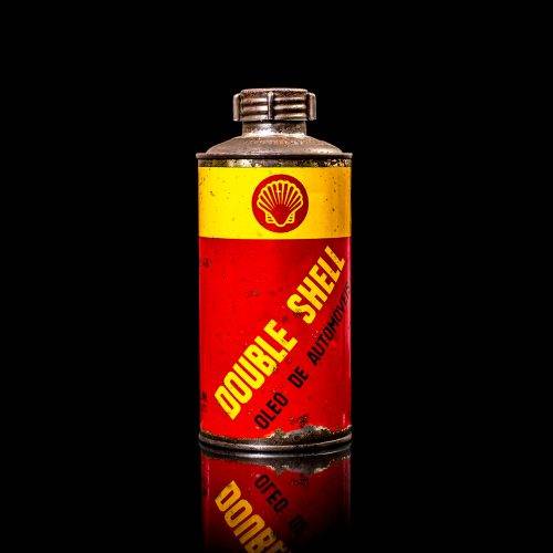 Vintage Shell oil cans with red and yellow branding from the 1900-1920 old logo Vintage Shell oil cans from 1900-19255, featuring the old logo. The photo showcases an antique tin red with yellow accents, displaying the historic Shell emblem. Shot in a studio against a solid black background
