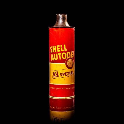 Vintage Shell oil cans with red and yellow branding from the 1900-1920 old logo Vintage Shell oil cans from 1900-19255, featuring the old logo. The photo showcases an antique tin red with yellow accents, displaying the historic Shell emblem. Shot in a studio against a solid black background