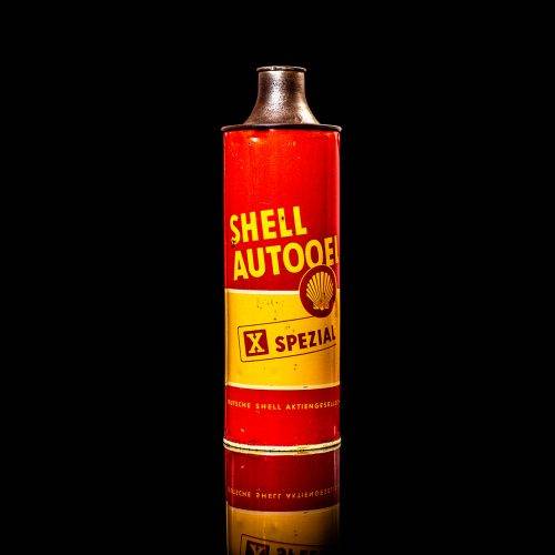 Vintage Shell oil cans with red and yellow branding from the 1900-1920 old logo Vintage Shell oil cans from 1900-19255, featuring the old logo. The photo showcases an antique tin red with yellow accents, displaying the historic Shell emblem. Shot in a studio against a solid black background