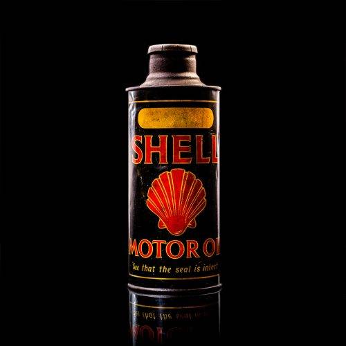 Vintage Shell oil cans with red and yellow branding from the 1900-1920 old logo Vintage Shell oil cans from 1900-19255, featuring the old logo. The photo showcases an antique tin red with yellow accents, displaying the historic Shell emblem. Shot in a studio against a solid black background