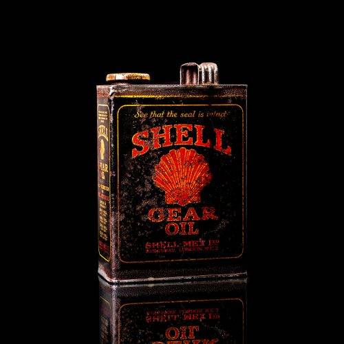 Vintage Shell oil cans with red and yellow branding from the 1900-1920 old logo Vintage Shell oil cans from 1900-19255, featuring the old logo. The photo showcases an antique tin red with yellow accents, displaying the historic Shell emblem. Shot in a studio against a solid black background