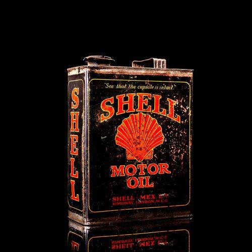 Vintage Shell oil cans with red and yellow branding from the 1900-1920 old logo Vintage Shell oil cans from 1900-19255, featuring the old logo. The photo showcases an antique tin red with yellow accents, displaying the historic Shell emblem. Shot in a studio against a solid black background