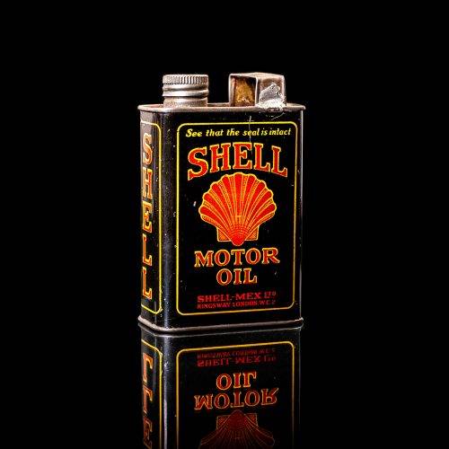 Vintage Shell oil cans with red and yellow branding from the 1900-1920 old logo Vintage Shell oil cans from 1900-19255, featuring the old logo. The photo showcases an antique tin red with yellow accents, displaying the historic Shell emblem. Shot in a studio against a solid black background