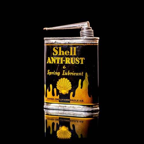 Vintage Shell oil cans with red and yellow branding from the 1900-1920 old logo Vintage Shell oil cans from 1900-19255, featuring the old logo. The photo showcases an antique tin red with yellow accents, displaying the historic Shell emblem. Shot in a studio against a solid black background
