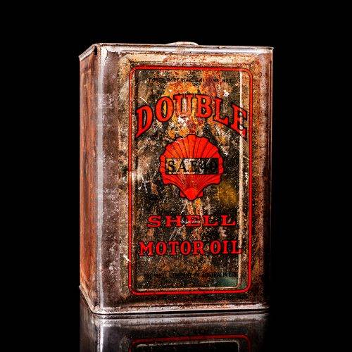 Vintage Shell oil cans with red and yellow branding from the 1900-1920 old logo Vintage Shell oil cans from 1900-19255, featuring the old logo. The photo showcases an antique tin red with yellow accents, displaying the historic Shell emblem. Shot in a studio against a solid black background