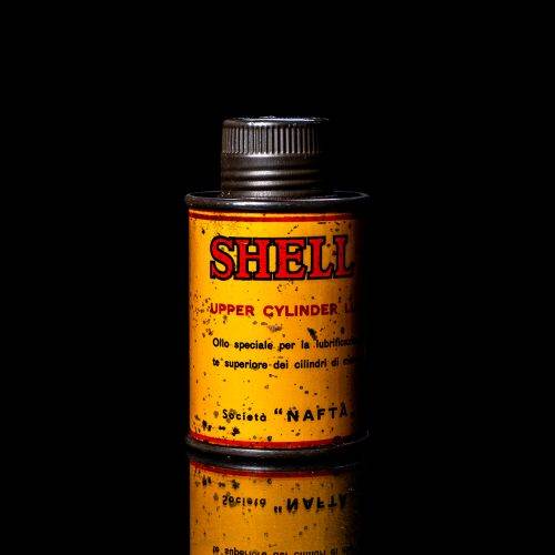 Vintage Shell oil cans with red and yellow branding from the 1900-1920 old logo Vintage Shell oil cans from 1900-19255, featuring the old logo. The photo showcases an antique tin red with yellow accents, displaying the historic Shell emblem. Shot in a studio against a solid black background