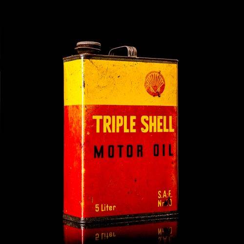 Vintage Shell oil cans with red and yellow branding from the 1900-1920 old logo Vintage Shell oil cans from 1900-19255, featuring the old logo. The photo showcases an antique tin red with yellow accents, displaying the historic Shell emblem. Shot in a studio against a solid black background