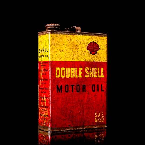 Vintage Shell oil cans with red and yellow branding from the 1900-1920 old logo Vintage Shell oil cans from 1900-19255, featuring the old logo. The photo showcases an antique tin red with yellow accents, displaying the historic Shell emblem. Shot in a studio against a solid black background