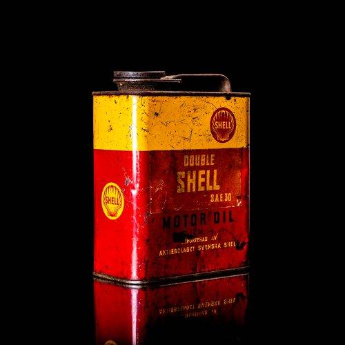 Vintage Shell oil cans with red and yellow branding from the 1900-1920 old logo Vintage Shell oil cans from 1900-19255, featuring the old logo. The photo showcases an antique tin red with yellow accents, displaying the historic Shell emblem. Shot in a studio against a solid black background