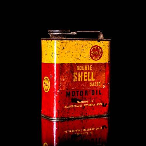 Vintage Shell oil cans with red and yellow branding from the 1900-1920 old logo Vintage Shell oil cans from 1900-19255, featuring the old logo. The photo showcases an antique tin red with yellow accents, displaying the historic Shell emblem. Shot in a studio against a solid black background