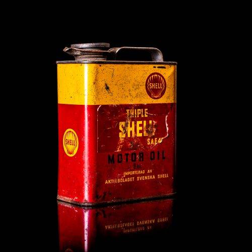 Vintage Shell oil cans with red and yellow branding from the 1900-1920 old logo Vintage Shell oil cans from 1900-19255, featuring the old logo. The photo showcases an antique tin red with yellow accents, displaying the historic Shell emblem. Shot in a studio against a solid black background
