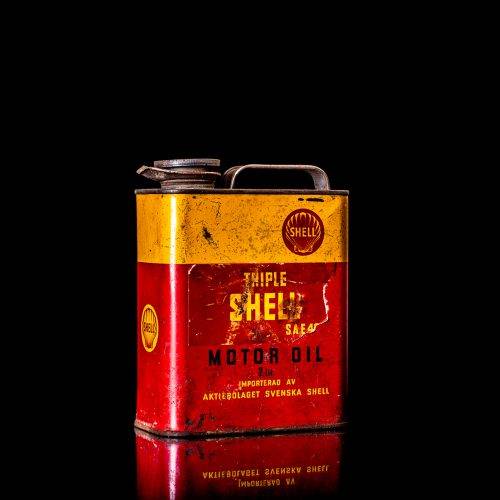 Vintage Shell oil cans with red and yellow branding from the 1900-1920 old logo Vintage Shell oil cans from 1900-19255, featuring the old logo. The photo showcases an antique tin red with yellow accents, displaying the historic Shell emblem. Shot in a studio against a solid black background