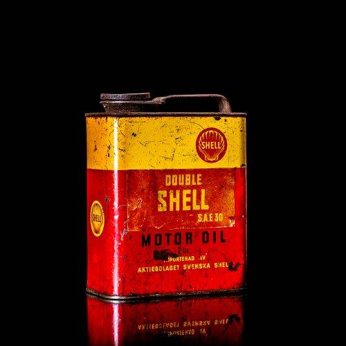 Vintage Shell oil cans with red and yellow branding from the 1900-1920 old logo Vintage Shell oil cans from 1900-19255, featuring the old logo. The photo showcases an antique tin red with yellow accents, displaying the historic Shell emblem. Shot in a studio against a solid black background