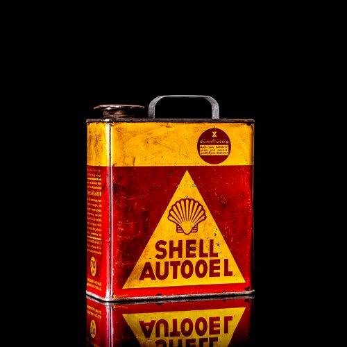 Vintage Shell oil cans with red and yellow branding from the 1900-1920 old logo Vintage Shell oil cans from 1900-19255, featuring the old logo. The photo showcases an antique tin red with yellow accents, displaying the historic Shell emblem. Shot in a studio against a solid black background